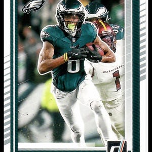 Puede incluir: Tarjeta de fútbol con Devonta Smith, receptor abierto de los Eagles, con uniforme verde y blanco, sosteniendo un balón. La tarjeta tiene un borde verde y el logotipo de Donruss.