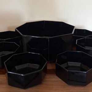 Peut inclure: Un ensemble de sept bols octogonaux noirs brillants de tailles variées. La collection comprend un grand bol central entouré de six bols plus petits, tous dotés d'une finition lisse et réfléchissante avec des formes géométriques à huit côtés.