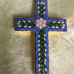 May include: A mosaic cross pendant with a gold-tone bail. The cross features a blue border, green and white center design, and pink floral accents. The pendant is likely made of glass or stone.