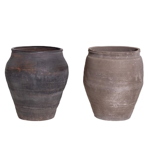 May include: Two antique, rustic ceramic pots. The pot on the left is dark brown with a textured surface. The pot on the right is a lighter, grey-brown color. Both pots have a wide, rounded body and a narrow neck.