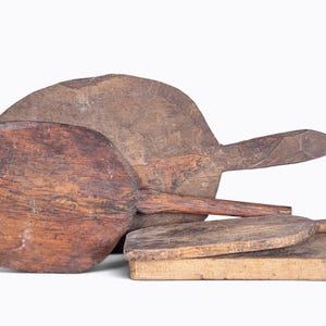 Peut inclure: Un ensemble de quatre planches à découper en bois patiné dotées de manches. Les planches présentent des formes variées, rondes et rectangulaires, avec des nuances de brun, un grain apparent, des textures de surface et des marques d'usure.