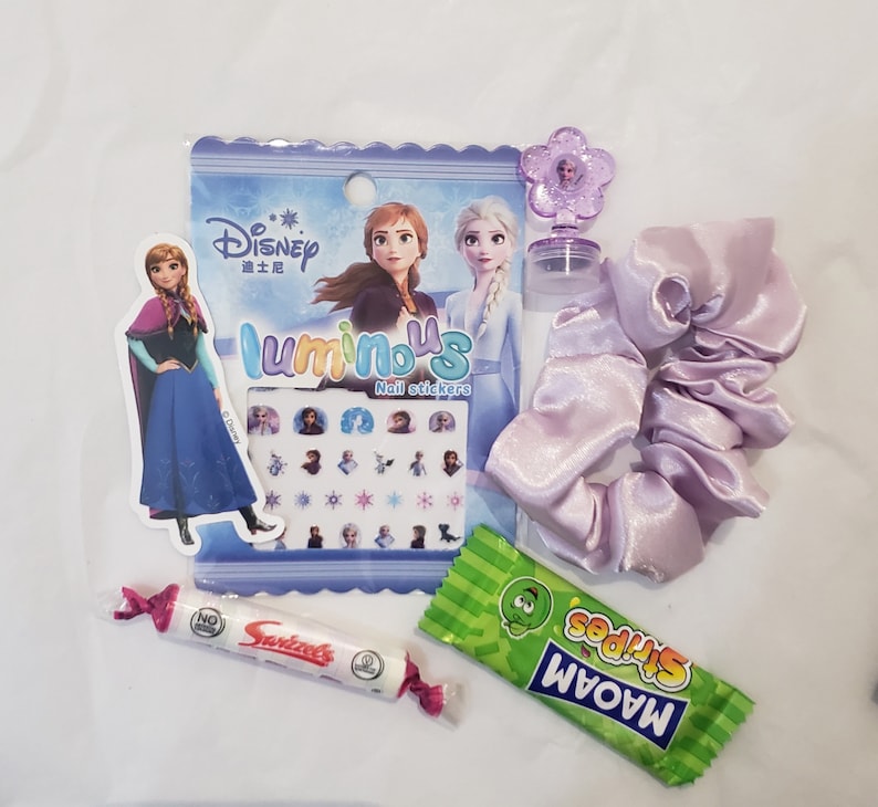May include: A Frozen themed party favor bag with a purple hair scrunchie, a pack of nail stickers, a small bottle of nail polish, a pack of candy, and a small plastic flower charm.