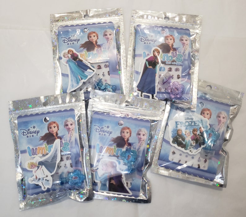 May include: Six small plastic bags with silver holographic backgrounds containing Disney Frozen themed stickers and nail art. The bags feature images of Elsa, Anna, and Olaf.