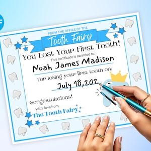 May include: A blue and white certificate with a tooth fairy design. It says "You Lost Your First Tooth!" and is addressed to "Noah James Madison" for losing his first tooth on "July 18, 202".