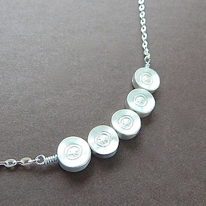 May include: A silver necklace with a curved row of five round pendants, each with a small clear stone in the center.