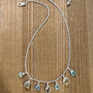 May include: A silver chain necklace with teardrop-shaped gemstones in shades of blue and yellow.