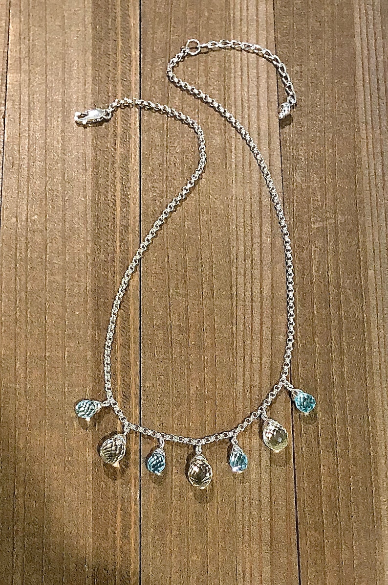 May include: A silver chain necklace with teardrop-shaped gemstones in shades of blue and yellow.