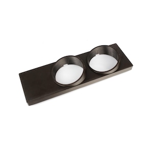 Puede incluir: Un portavasos doble de plástico negro con dos aberturas circulares. El portavasos está diseñado para encajar en el tablero de un automóvil.