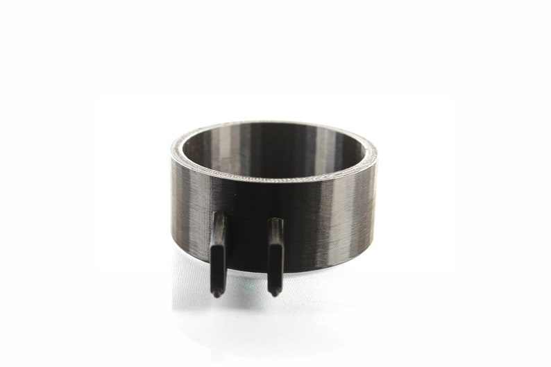 K&ouml;nnte beinhalten: Ein schwarzer und grauer 3D-gedruckter Ring mit zwei Zacken, die von unten herausragen.
