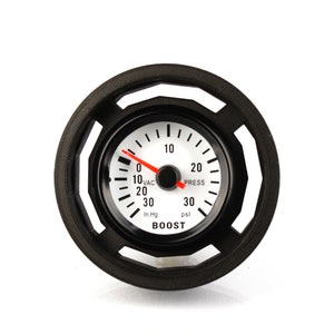May include: A white boost gauge with a black bezel and a red needle. The gauge has markings for both inches of mercury and pounds per square inch. The gauge reads "BOOST" and has a black background.