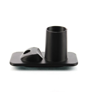 Może przedstawiać: Czarna plastikowa podstawa z okrągłym, czarnym plastikowym wkładką. Podstawa ma mały otwór w środku.