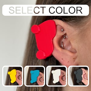 May include: A red ear support device with two circular protrusions, designed to provide support. The image also shows the device in yellow, blue, white, and black. The text "SELECT COLOR" is displayed at the top of the image.