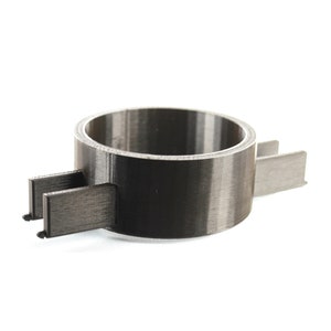 K&ouml;nnte beinhalten: Ein schwarzer 3D-gedruckter Ring mit zwei Armen, die sich zu den Seiten erstrecken. Der Ring ist so konzipiert, dass er etwas an Ort und Stelle h&auml;lt.