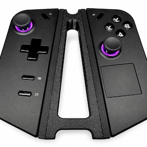 Può includere: Un controller di gioco portatile nero dotato di due levette analogiche con illuminazione circolare viola, un pad direzionale, quattro pulsanti azione etichettati X, Y, A e B, due pulsanti menu e un touchpad quadrato, montato su un telaio nero.