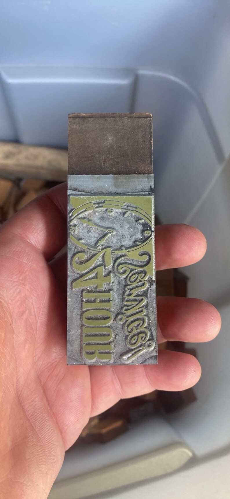 May include: A rectangular metal printing block with the words "4 Hour Service" and "Tennice" in a stylized font. The block has a green and silver design with a clock face.