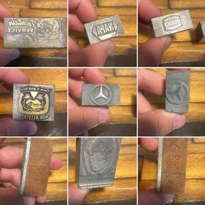 May include: Collection of vintage metal printing blocks. The blocks feature various designs, including text, logos, and illustrations. Some blocks have text that reads "Fountain Service" and "NAPA". Other blocks feature a Mercedes-Benz logo and a house illustration.