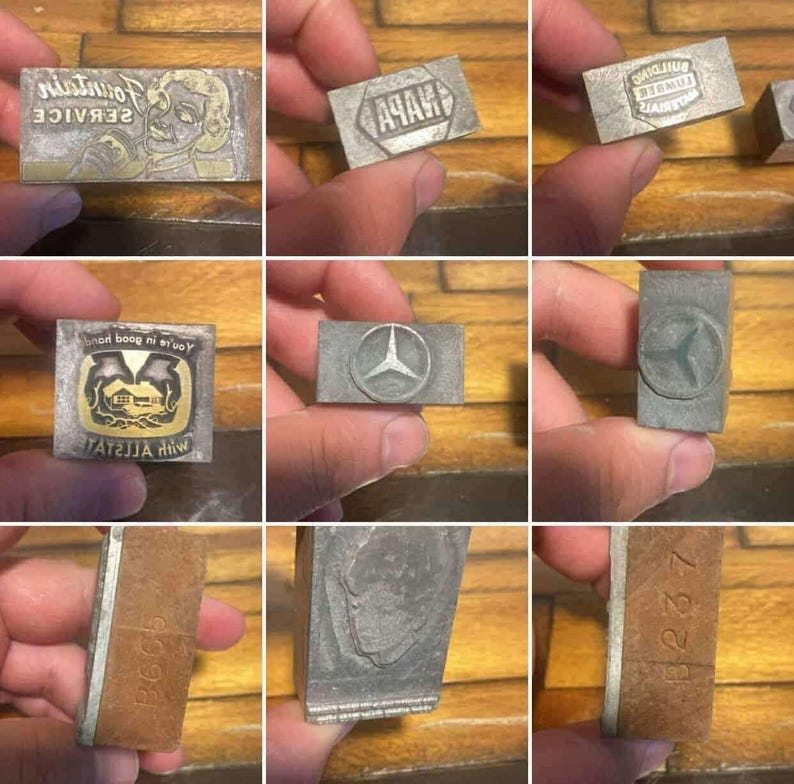 May include: Collection of vintage metal printing blocks. The blocks feature various designs, including text, logos, and illustrations. Some blocks have text that reads "Fountain Service" and "NAPA". Other blocks feature a Mercedes-Benz logo and a house illustration.