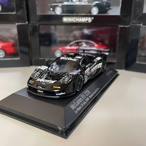 Puede incluir: Un modelo de coche de carreras McLaren F1 GTR negro con detalles blancos y el texto "Le Mans 24 hrs. 1998 Bschep" y "McLaren F1 GTR" en la base.