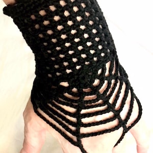 May include: Black crocheted wrist cuff with a spiderweb design. The cuff is made of a fine yarn and has a delicate, lacy look.