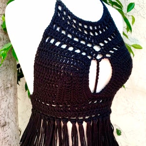May include: Black crochet halter top with fringe trim. The top has a cutout detail in the front.