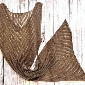 Pode incluir: Um xale e um top a condizer em malha castanha de tecido aberto. O xale &eacute; triangular e o top tem decote em V e design sem mangas. Ambas as pe&ccedil;as apresentam um padr&atilde;o de espinha de peixe e s&atilde;o exibidas numa superf&iacute;cie de madeira branca.