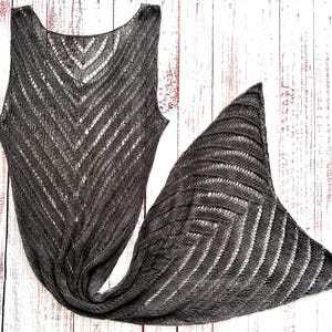 Pode incluir: Um top sem mangas e um cachecol a condizer, cinza escuro, de malha. O top apresenta um decote redondo e um padr&atilde;o em ziguezague. O cachecol triangular tem um design semelhante. Ambos os artigos s&atilde;o feitos de tecido leve e vazado, ideal para sobrepor.