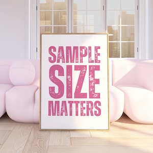 May include: A framed print with the text "SAMPLE SIZE MATTERS" in pink lettering on a white background. The print is displayed in a room with two pink couches.