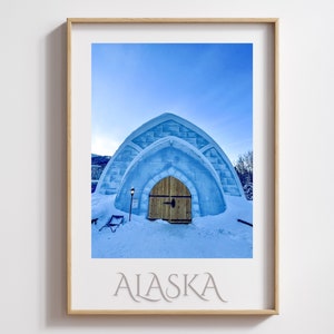 May include: A blue ice hotel with a wooden door in the middle of a snowy landscape. The text "ALASKA" is printed below the image.