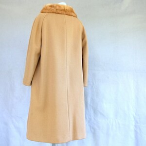 Back of vintage 1950's light brown, fur collared Holly Gab winter coat with a light brown mink fur collar & a double breasted front. There are 2 hooks on the removable collar that will snug the blonde fur, with a snap underneath. The front buttons. The 3/4 length sleeves are cut-on with a seam down the outside as well as the usual one underneath. There are 2 pockets in the front side seams with faux welts. It is lined with satin that has a backing of what looks like a loosely woven gray wool.
