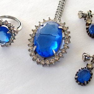 vintage Avon blue crystal glass set includes a necklace whose pendant may be used as a brooch, an adjusting ring, and a pair of dangle post earrings.