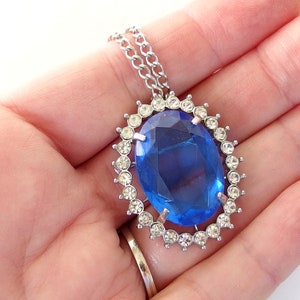 vintage Avon blue crystal glass set includes a necklace whose pendant may be used as a brooch, an adjusting ring, and a pair of dangle post earrings.