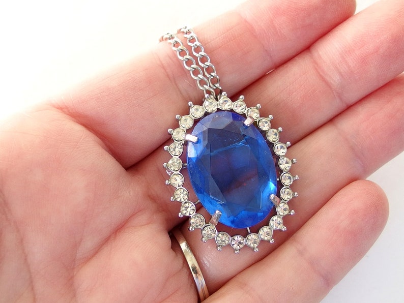 vintage Avon blue crystal glass set includes a necklace whose pendant may be used as a brooch, an adjusting ring, and a pair of dangle post earrings.