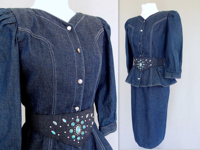May include: This denim peplum suit is vintage 1980's.  
The jacket has a wide V neckline, silver buttons up the front, puffy 3/4 length sleeves with a single button cuff, and a super flared hemline to create a peplum.  Accented with white topstitching. 

The rigid, obi style belt has faux turquoise  and silver studs.

The unlined  pencil skirt has a slit in the back for wearing ease and a back zipper.