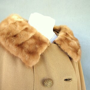 Vintage 1950's light brown, fur collared Holly Gab winter coat features a light brown mink fur collar & a double breasted front. There are 2 hooks on the removable collar that will snug the blonde fur, with a snap underneath. The front buttons. The 3/4 length sleeves are cut-on with a seam down the outside as well as the usual one underneath. There are 2 pockets in the front side seams with faux welts. It is lined with satin that has a backing of what looks like a loosely woven gray wool.