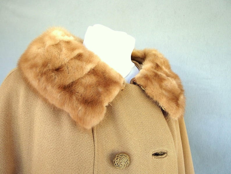 Vintage 1950's light brown, fur collared Holly Gab winter coat features a light brown mink fur collar & a double breasted front. There are 2 hooks on the removable collar that will snug the blonde fur, with a snap underneath. The front buttons. The 3/4 length sleeves are cut-on with a seam down the outside as well as the usual one underneath. There are 2 pockets in the front side seams with faux welts. It is lined with satin that has a backing of what looks like a loosely woven gray wool.