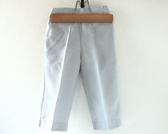 May include: Light gray pants hanging on a wooden hanger. The pants have a straight leg and a flat front.