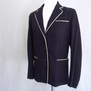 May include: A navy blue blazer with a white trim around the collar, pockets, and cuffs.