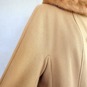 Vintage 1950's light brown, fur collared Holly Gab winter coat features a light brown mink fur collar & a double breasted front. There are 2 hooks on the removable collar that will snug the blonde fur, with a snap underneath. The front buttons. The 3/4 length sleeves are cut-on with a seam down the outside as well as the usual one underneath. There are 2 pockets in the front side seams with faux welts. It is lined with satin that has a backing of what looks like a loosely woven gray wool.