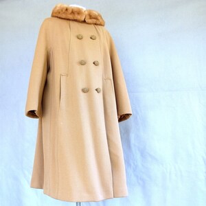 Vintage 1950's light brown, fur collared Holly Gab winter coat features a light brown mink fur collar & a double breasted front. There are 2 hooks on the removable collar that will snug the blonde fur, with a snap underneath. The front buttons. The 3/4 length sleeves are cut-on with a seam down the outside as well as the usual one underneath. There are 2 pockets in the front side seams with faux welts. It is lined with satin that has a backing of what looks like a loosely woven gray wool.