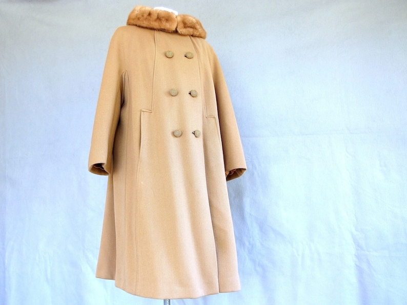 Vintage 1950's light brown, fur collared Holly Gab winter coat features a light brown mink fur collar & a double breasted front. There are 2 hooks on the removable collar that will snug the blonde fur, with a snap underneath. The front buttons. The 3/4 length sleeves are cut-on with a seam down the outside as well as the usual one underneath. There are 2 pockets in the front side seams with faux welts. It is lined with satin that has a backing of what looks like a loosely woven gray wool.