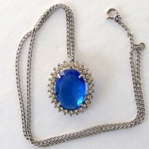 vintage Avon blue crystal glass set includes a necklace whose pendant may be used as a brooch, an adjusting ring, and a pair of dangle post earrings.