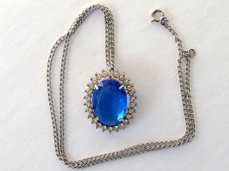vintage Avon blue crystal glass set includes a necklace whose pendant may be used as a brooch, an adjusting ring, and a pair of dangle post earrings.