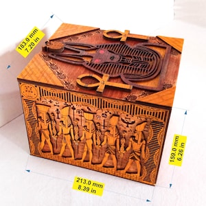 May include: Wooden box with intricate carvings of Egyptian gods and symbols. The box is 7.20 inches tall, 8.39 inches wide, and 6.26 inches deep.