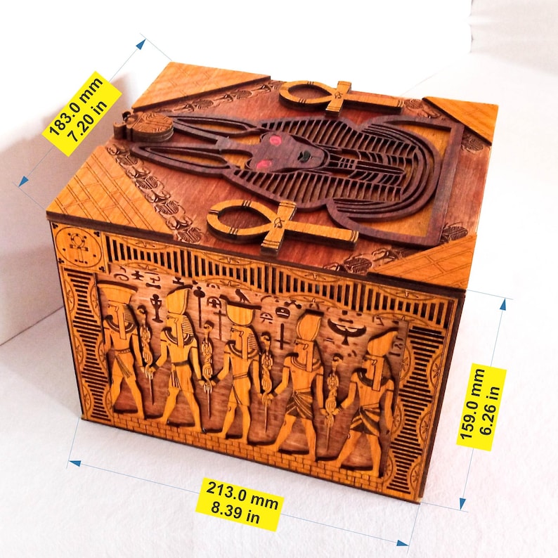 May include: Wooden box with intricate carvings of Egyptian gods and symbols. The box is 7.20 inches tall, 8.39 inches wide, and 6.26 inches deep.
