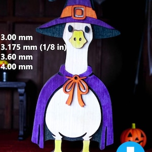 May include: A wooden Halloween decoration of a goose wearing a witch hat and cape. The goose is white with a yellow beak and feet, and the hat and cape are purple. The image includes the text "DXF PDF SVG CDR AI" and measurements in millimeters and inches.
