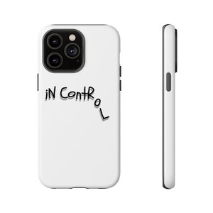 Può includere: Custodia per telefono bianca con un obiettivo della fotocamera nero e il testo "IN CONTROL" scritto in corsivo nero.