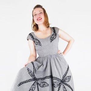 Schwarz-weiß kariertes Kleid aus den 1950er Jahren mit weitem Rock, Paillettenbesatz und Borte. Original von S Jay – Mel Warshaw Inc., Miami – VFG-Mitglied