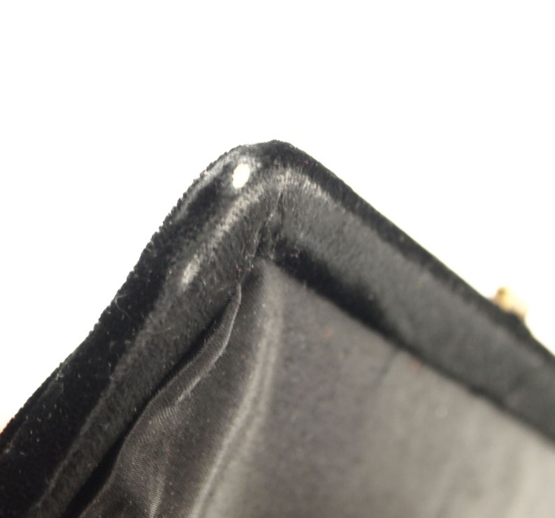 Puede incluir: Primer plano del forro de terciopelo negro de una caja. El forro es suave y mullido, con un brillo sutil.
