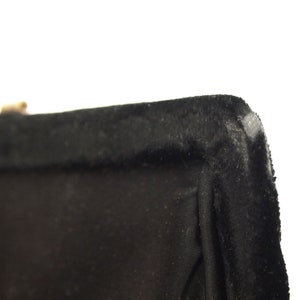 Puede incluir: Primer plano del borde superior de una bolsa de terciopelo negro. El borde est&aacute; cosido con un hilo negro grueso.