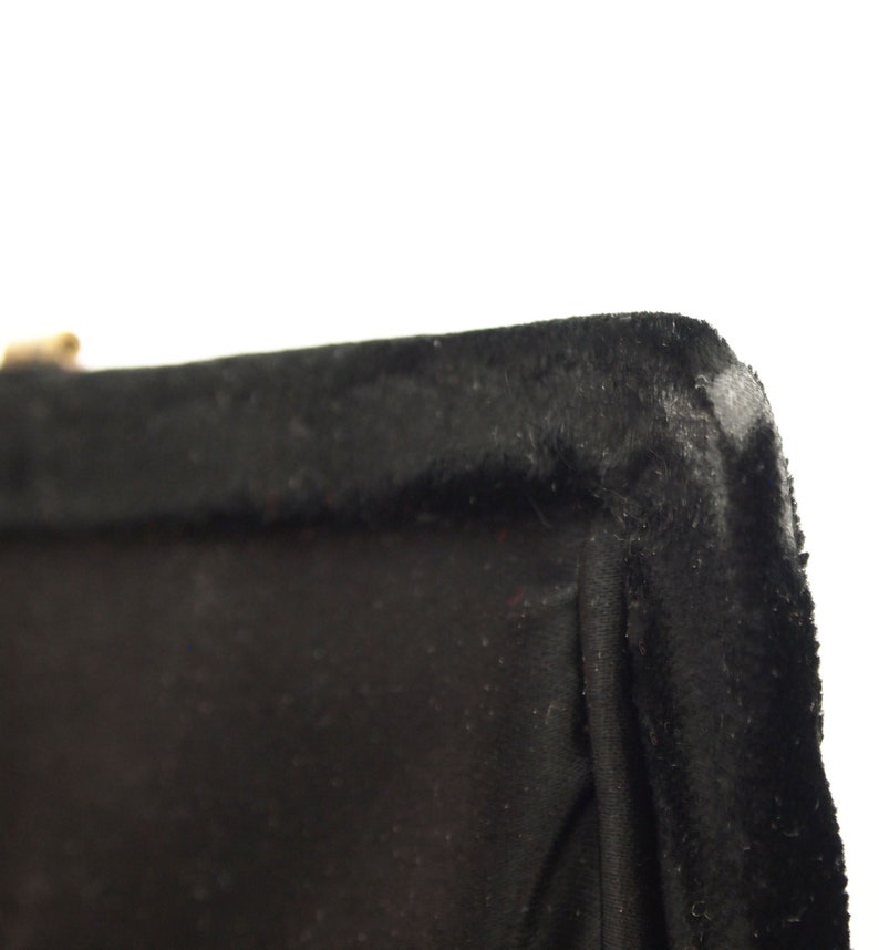 Puede incluir: Primer plano del borde superior de una bolsa de terciopelo negro. El borde est&aacute; cosido con un hilo negro grueso.